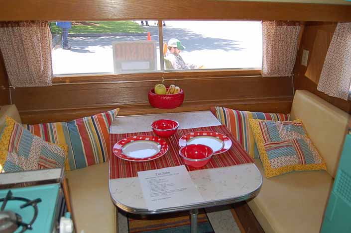 Photo shows a beautifully restored dining area in a vintage Aladdin Genie travel trailer